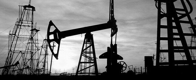 Oil derricks are silhouetted against the rising sun at oilfield in the capital Baku
