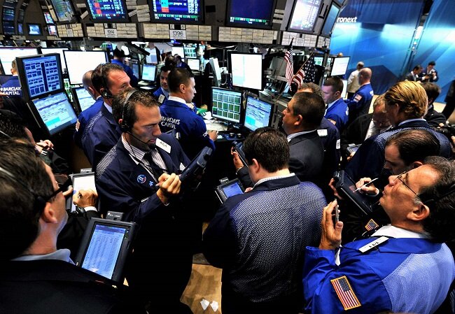 Traders crowd around a post on the floor